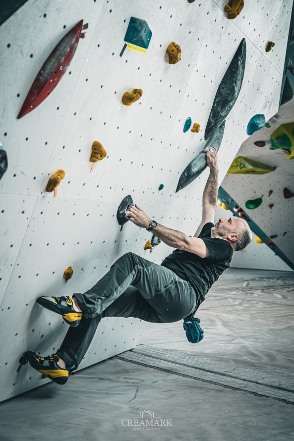 Escaladeur de bloc tient sur mur blanc et bleu